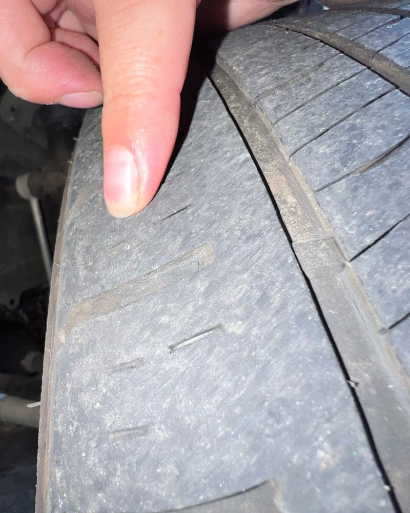 A technician's finger on a worn front tire during one of our inspections